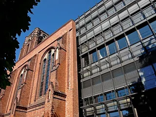 Kirchenfassade neben einem modernen Gebäude.
