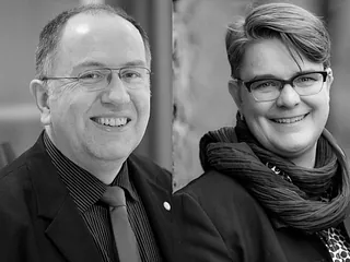 Two men, one smiling, in black and white.