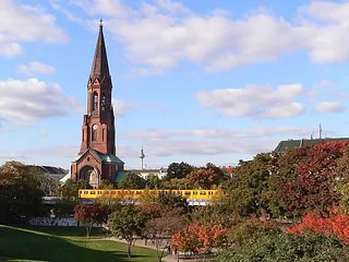 Kirchturm mit Berliner Skyline im Hintergrund.