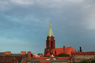 Rote Backsteinkirche mit grünem Turm.