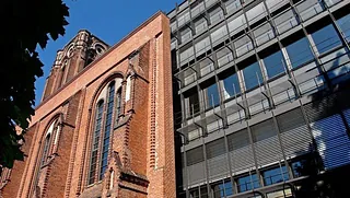 Detailaufnahme der Fassade eines roten Backsteingebäudes mit gotischen Fenstern.