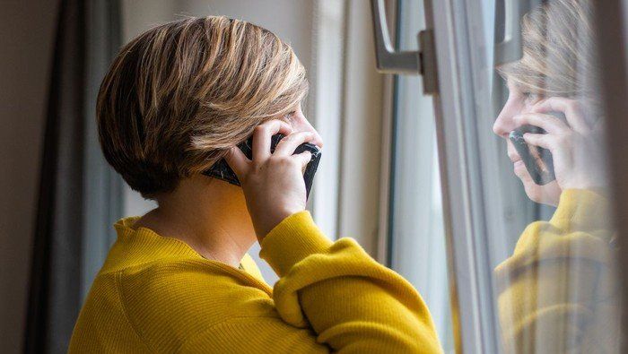 Person telefoniert und schaut aus dem Fenster.