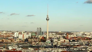 Panorama der Berliner Innenstadt mit dem Fernsehturm unter blauem Himmel.