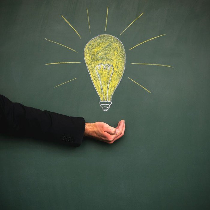 Hand unter einer gezeichneten Glühbirne.